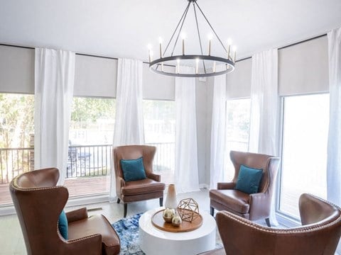 a living room with chairs and a round table and a chandelier